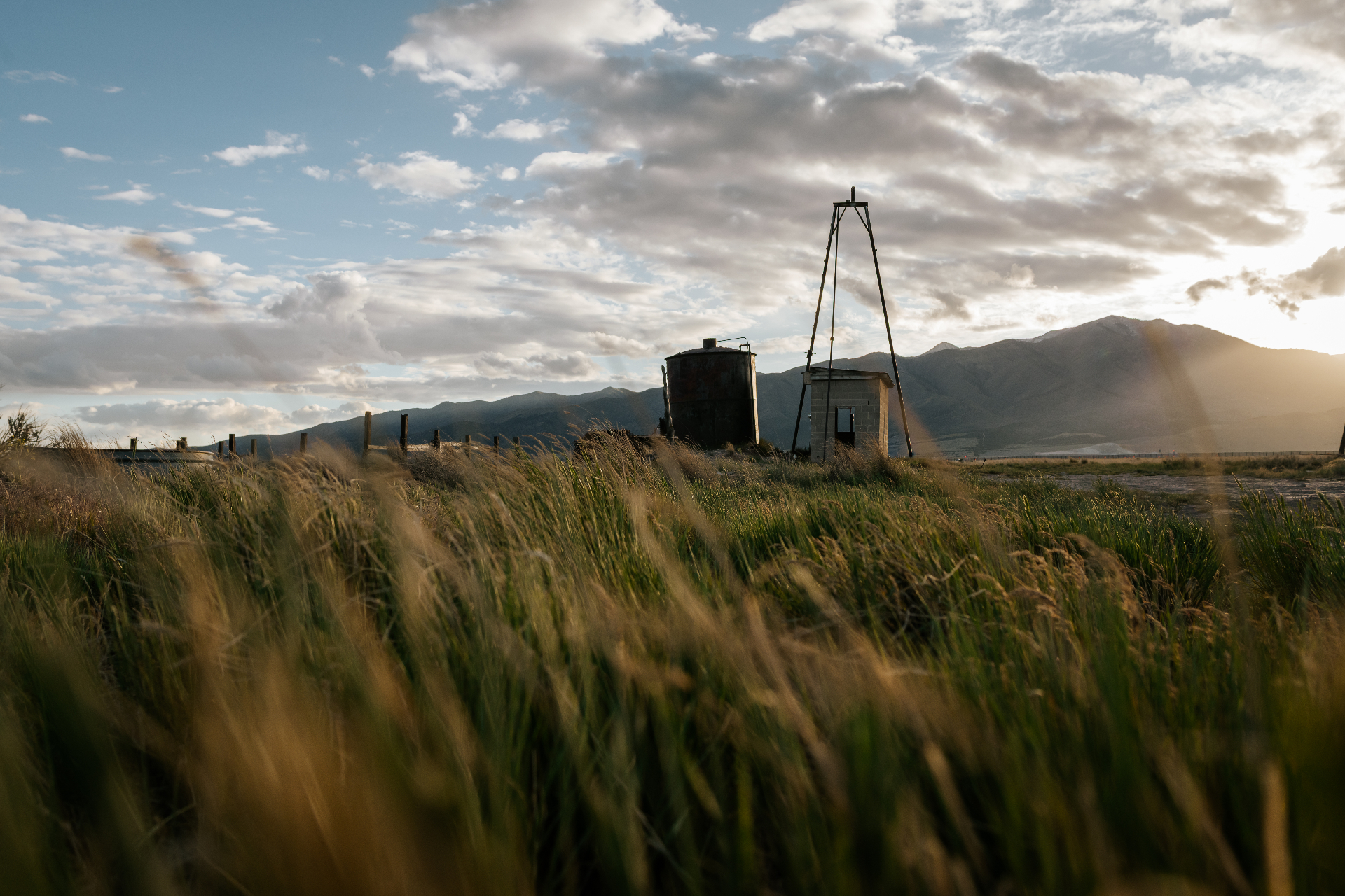 Tall grass and old water tank with Eagle Mountain peaks behind